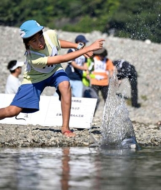 　「第２３回仁淀川国際水切り大会」で石を投げる参加者＝１１日午前、高知県いの町