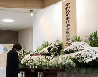 　宮城県丸森町の追悼行事で献花し、手を合わせる天野民子さん＝１２日午前、丸森町