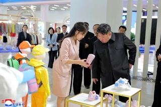　北朝鮮国内で生産されたアパレル商品の展示会を視察する金正恩朝鮮労働党総書記（手前右）と娘＝１９日、平壌（朝鮮通信＝共同）