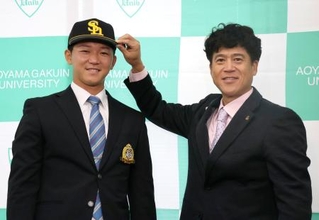 　城島ＣＢＯ（右）から帽子をかぶせてもらうソフトバンク１位指名の青学大・鈴木泰成投手＝２３日、東京都