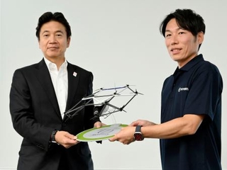 　空飛ぶクルマの模型を手に写真に納まる三菱ＵＦＪ銀行の北村慎取締役専務執行役員（左）＝６日、大阪市