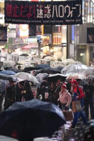 　２０２５年１０月のハロウィーンで、雨が降る東京・渋谷を歩く人たち