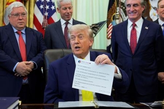 　「トゥルース・ソーシャル」への投稿を印刷した紙を掲げるトランプ米大統領＝６月、ワシントンのホワイトハウス（ロイター＝共同）