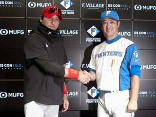 　握手を交わす日本ハムの新庄監督（左）と西岡新野手総合コーチ＝３１日、エスコンフィールド