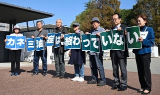 　カネカの高砂工場前でメッセージを掲げる「カネミ油症」の被害者ら＝３１日午前、兵庫県高砂市