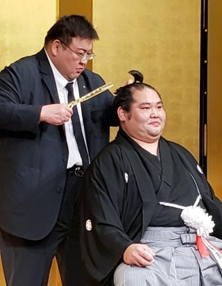 　断髪式で、追手風親方（左）に最後のはさみを入れられる元幕内大奄美の坂元元規氏＝３１日、福岡市内のホテル