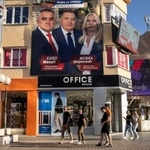 　ボスニア・ヘルツェゴビナ北部バニャルカで、総選挙の候補者が写った看板の前を通る人たち＝３日（ロイター＝共同）