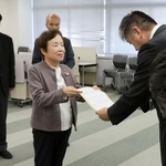 　富山市役所で中田祐一企画管理部次長（右）に要請書を手渡す市民団体の広瀬妙子代表委員＝８日午後