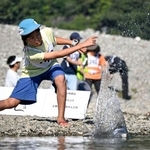 　「第２３回仁淀川国際水切り大会」で石を投げる参加者＝１１日午前、高知県いの町