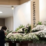 　宮城県丸森町の追悼行事で献花し、手を合わせる天野民子さん＝１２日午前、丸森町