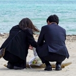 　沖縄県名護市辺野古の浜に花を手向ける武石知華さんの両親＝１８日午後