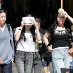 　強い日差しの下、大阪・道頓堀を歩く人たち＝２１日午前