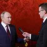 　２２日、モスクワでロシア国営テレビ記者の質問に答えるプーチン大統領（左）（ロシア大統領府提供・タス＝共同）