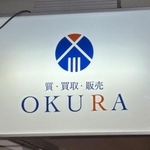 　高級腕時計の中古品販売を手がける「ＯＫＵＲＡ」の看板＝２３日午後、福岡市中央区