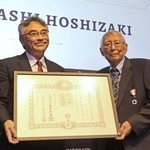 　２３日、室田幸靖駐ロサンゼルス総領事（左）から勲記を手渡されたタカシ・ホシザキさん＝米ロサンゼルス（共同）