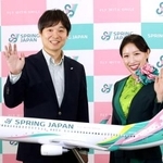 　新しいデザインの機体の模型と写真に納まる「スプリング・ジャパン」の浅見達朗社長（左）＝２６日午前、成田空港