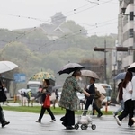 　雨が降る中、傘を差して熊本市内を歩く人たち。奥は熊本城＝２６日午前