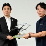 　空飛ぶクルマの模型を手に写真に納まる三菱ＵＦＪ銀行の北村慎取締役専務執行役員（左）＝６日、大阪市