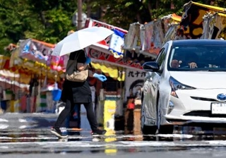 　気温４０度に迫る猛暑日となった三重県桑名市で、日傘を差して歩く人＝２日午後