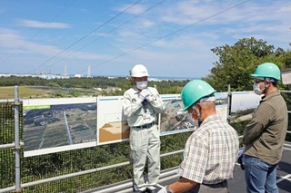 　中間貯蔵施設を巡るバスツアーの参加者に説明する施設の職員（奥）＝９日午後、福島県大熊町