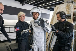 　地球に帰還し手を振る大西卓哉飛行士。右奥は宇宙船クルードラゴン＝９日、米カリフォルニア州沖（ＮＡＳＡ提供・共同）