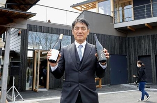 　福島県富岡町の「とみおかワイナリー」で、自社のワインを手にする遠藤秀文さん＝４月