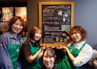 　スターバックスコーヒー店内に設置されたボードと写真に納まる「りんご隊」のメンバー＝６日、青森県弘前市
