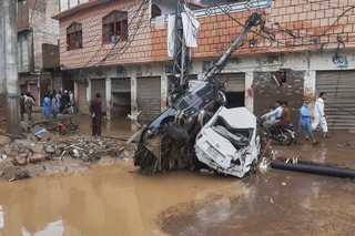 　豪雨による洪水で流され、電柱に衝突した車＝１５日、パキスタン北西部ミンゴラ近郊（ＡＰ＝共同）