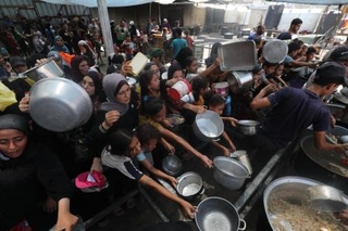 　ガザ中部ヌセイラト難民キャンプで、配給の食べ物を受け取ろうとする人たち＝１６日（ゲッティ＝共同）