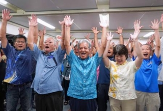 　沖縄県与那国町長選で初当選を決め、万歳する上地常夫氏（中央）＝２４日夜、与那国町