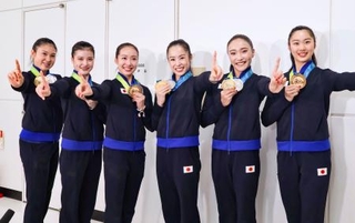 　帰国した成田空港でポーズをとる新体操の世界選手権で団体総合初の金メダルを獲得した鈴木歩佳（中央右）ら日本代表＝２６日