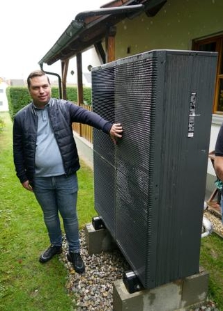 　導入したパナソニックのヒートポンプ式暖房機の室外機と利用者のクリストフ・ラウフマンさん＝２８日、ドイツ南部バイエルン州（共同）
