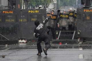 　３１日、インドネシア・ジャカルタの議会付近で警官隊に石を投げつけるデモ参加者（ＡＰ＝共同）