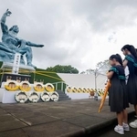 　長崎市の平和公園を訪れ、平和祈念像の前で手を合わせる女の子ら＝９日午後