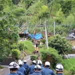 　大雨で土砂が流入し倒壊した住宅（奥）に向かう警察官ら＝１０日午前、鹿児島県姶良市