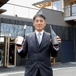 　福島県富岡町の「とみおかワイナリー」で、自社のワインを手にする遠藤秀文さん＝４月