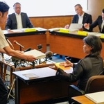 　静岡県伊東市議会の百条委員会で証人尋問に応じ、確認のために東洋大の卒業アルバムを受け取る田久保真紀市長（右）＝１３日午前
