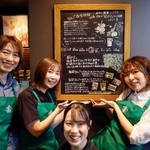 　スターバックスコーヒー店内に設置されたボードと写真に納まる「りんご隊」のメンバー＝６日、青森県弘前市