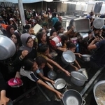 　ガザ中部ヌセイラト難民キャンプで、配給の食べ物を受け取ろうとする人たち＝１６日（ゲッティ＝共同）