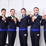 　帰国した成田空港でポーズをとる新体操の世界選手権で団体総合初の金メダルを獲得した鈴木歩佳（中央右）ら日本代表＝２６日