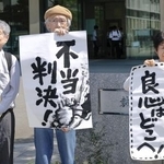 　九州電力川内原発１、２号機を巡る訴訟の控訴審判決で、請求を退けられ「不当判決」などと書かれた紙を掲げる原告団のメンバーら＝２７日午後、福岡高裁前