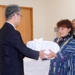 　遺骨を受け取る釧路アイヌ協会の桃井芳子会長（右）＝３０日午前、北海道釧路市