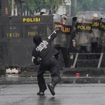 　３１日、インドネシア・ジャカルタの議会付近で警官隊に石を投げつけるデモ参加者（ＡＰ＝共同）