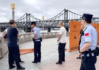 　中国遼寧省丹東で、鴨緑江沿いの遊歩道への立ち入りを規制する治安当局者ら。奥は「中朝友誼橋」＝１日（共同）
