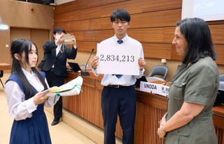 　２日、国連欧州本部で、反核署名の一部を国連軍縮部ジュネーブ事務所のレジンバル所長（右）に手渡す「高校生平和大使」＝スイス・ジュネーブ（共同）