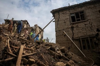 　８月３１日の地震で壊れた家と救助に当たる人たち＝９月２日、アフガニスタン東部クナール州（ロイター＝共同）