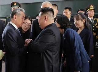 　２日、北京に到着し出迎えを受ける北朝鮮の金正恩朝鮮労働党総書記（手前左から２人目）。手前右端は娘＝２日（朝鮮中央通信＝共同）