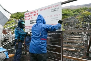 　富士山の登山道を冬季閉鎖するため、看板を設置する作業員＝１０日午後、静岡県富士宮市