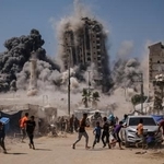　５日、イスラエル軍の攻撃で高層ビルが崩壊し、逃げる人々＝パレスチナ自治区ガザ市（ＡＰ＝共同）