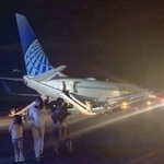 　関西空港に緊急着陸したユナイテッド航空機から、脱出用シューターを使って避難する乗客ら＝１２日午後（乗客提供）
